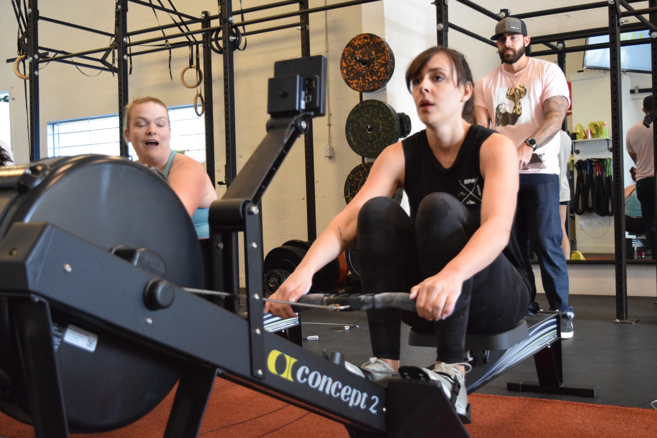 Two individuals participating in an indoor rowing workout at a fitness center.